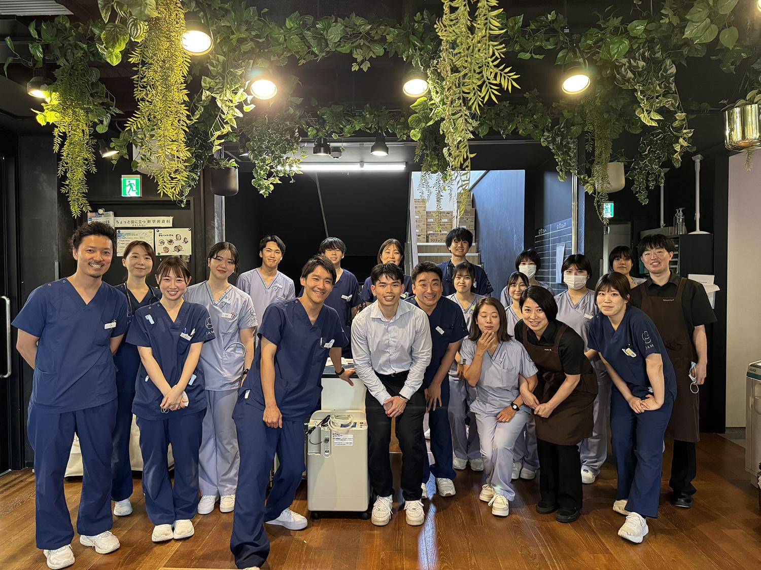 A group of people posing for a photo inside a room with plants hanging from the ceiling.