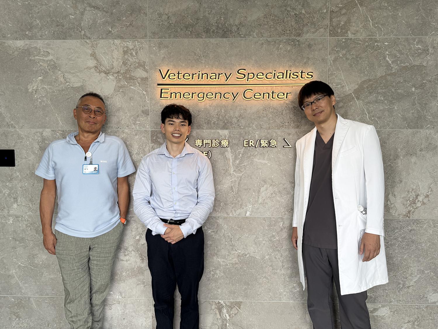 Three people standing in front of a wall with a sign that reads Veterinary Specialists Emergency Center."