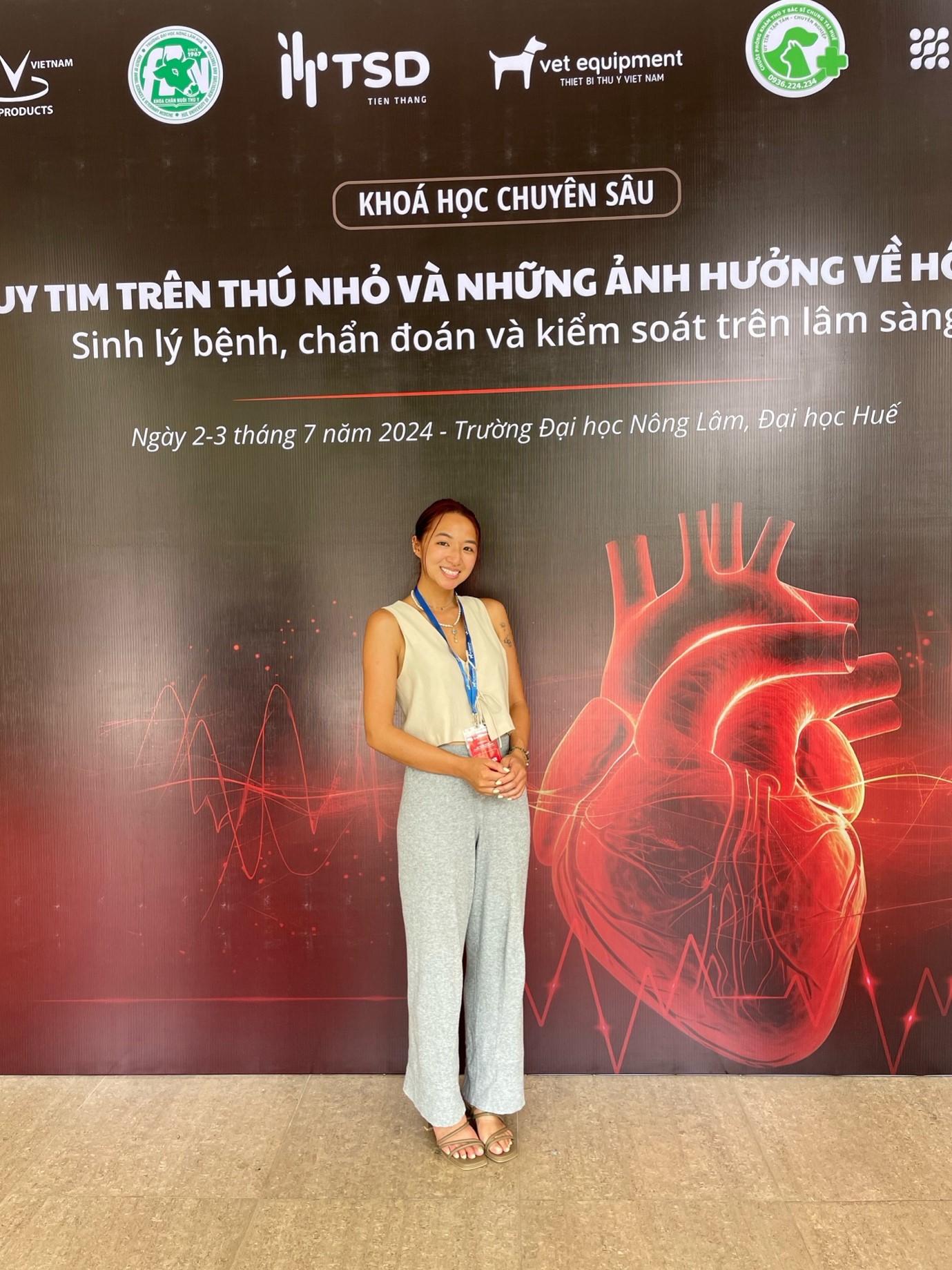 Nhung standing in front of a large poster that shows an illustration of a heart.