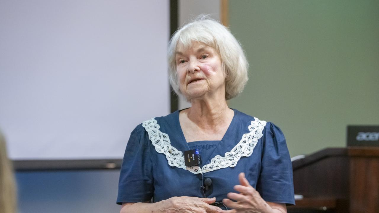 Dr. Lynette Hart standing in front of a screen and podium in a lecture hall.