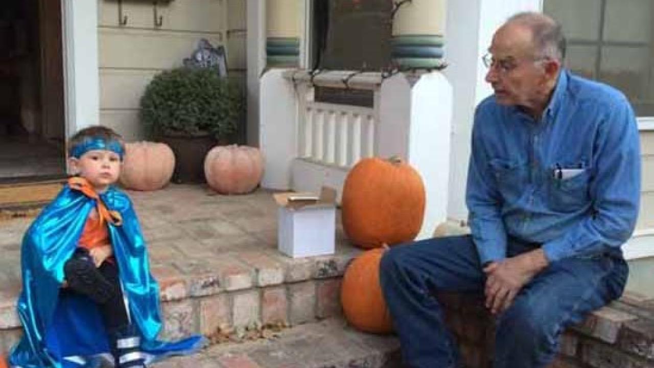 man sitting on porch with child in Halloween costume