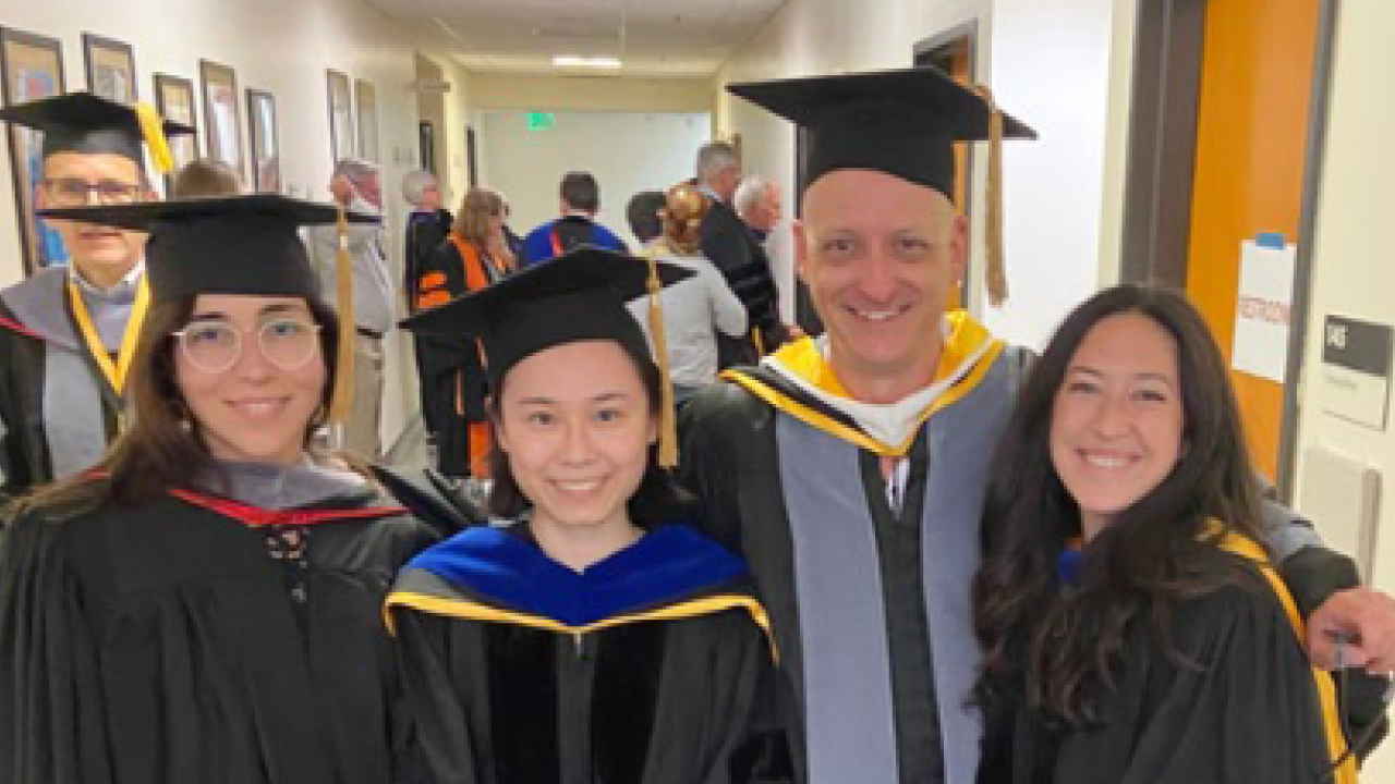 four veterinarians in graduation caps and gowns