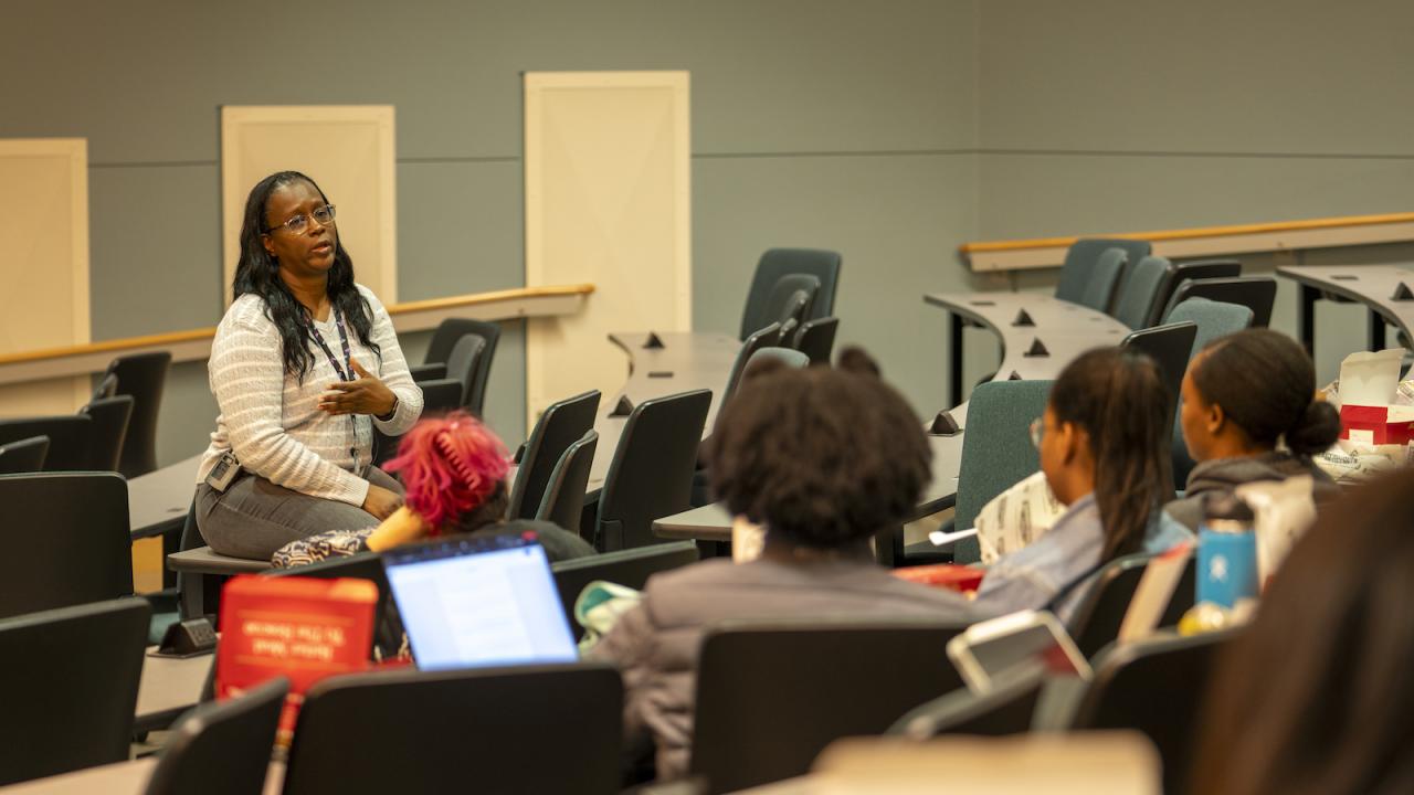 Dr. Gina Davis sitting in a classroom addressing students during a VOICE lunch talk