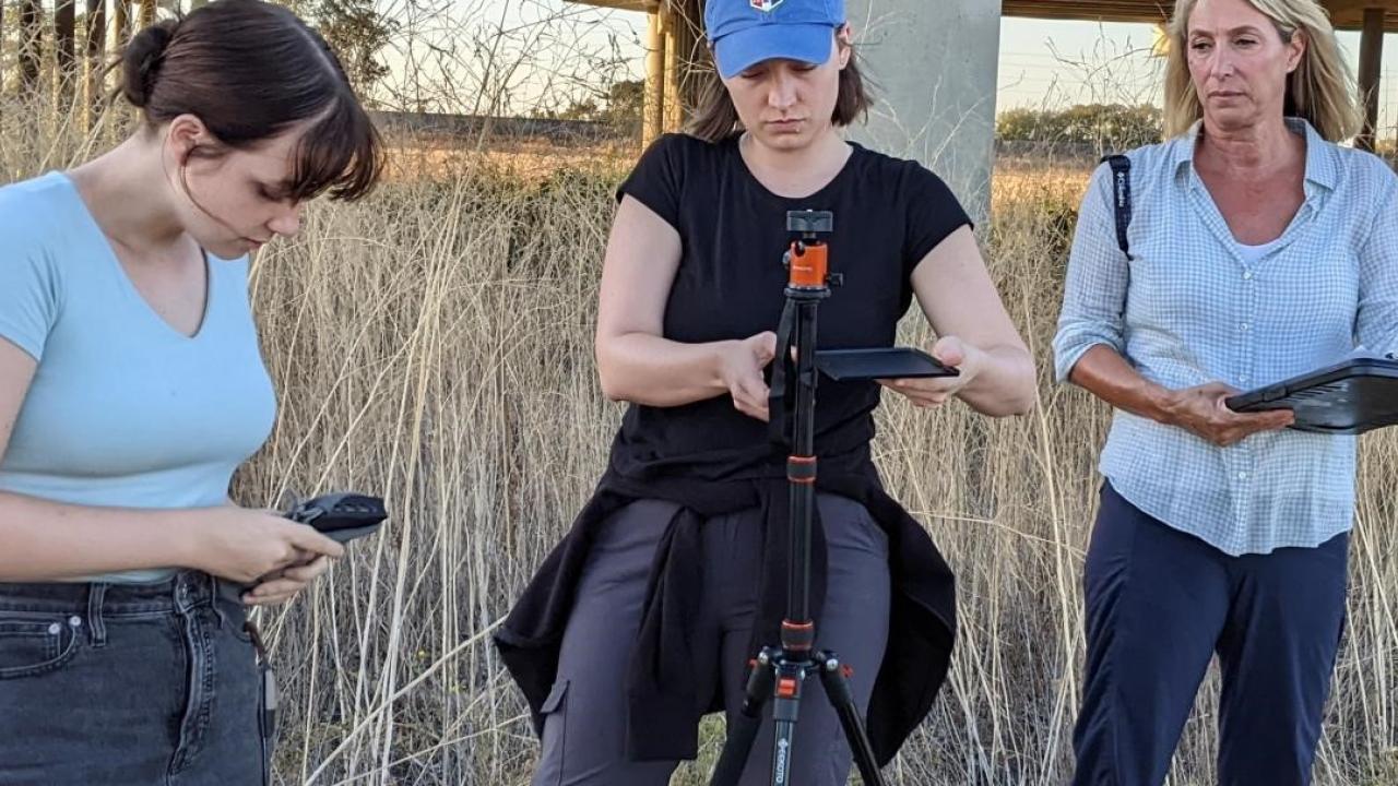 three women setting up equipment in field