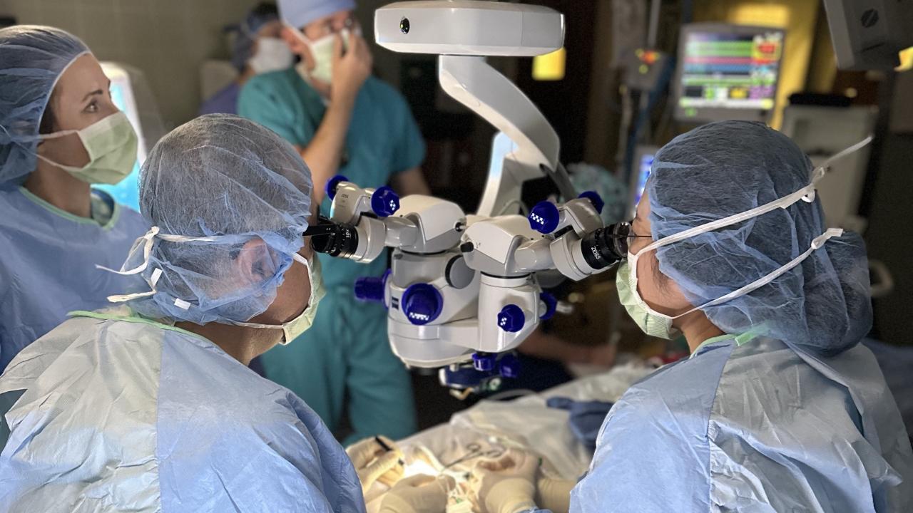 surgeons looking through a microscope over a patient in the operating room