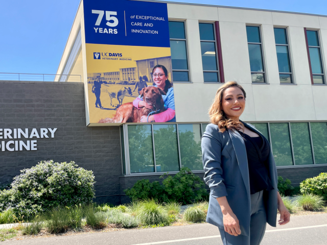 Dr. Jovanna Radillo stands below building banner bearing her image.