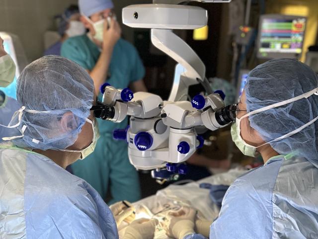surgeons looking through a microscope over a patient in the operating room