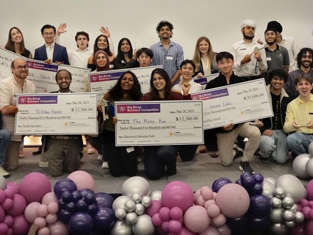 group of students celebrating with balloons and large checks