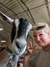 goat and woman with heads together looking into camera