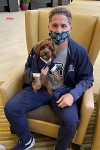 man sitting in chair holding small dog