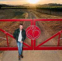 Man standing at ranch gate with sunset in background