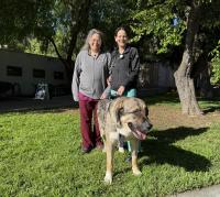 two veterinarians standing with dog on grass