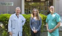 three people in front of the UC Davis veterinary hospital