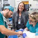 Medical team in teal scrubs attending to animal on exam table, smiling supervisor behind
